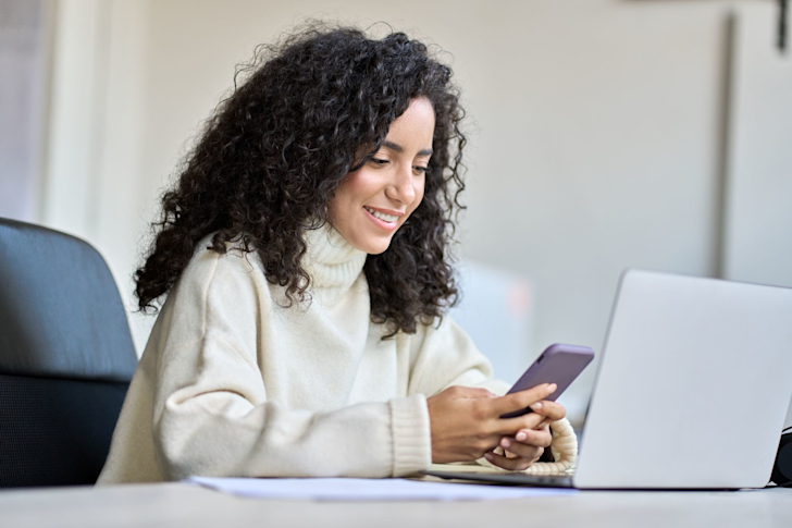 vrouw met laptop en telefoon in handen