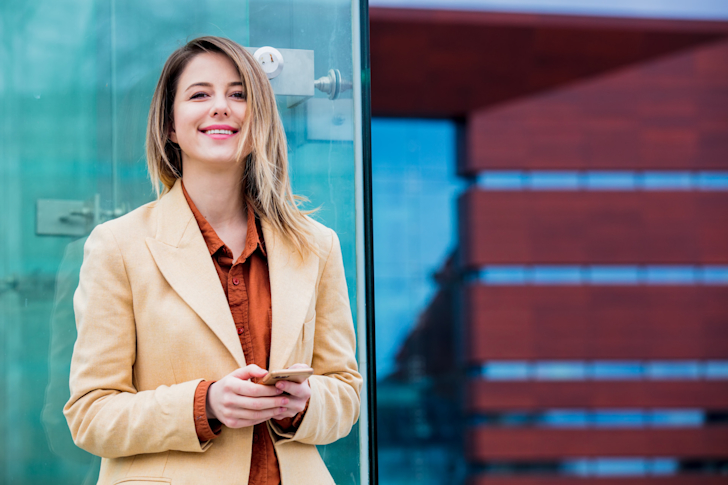 ondernemer-vrouw-telefoon-bank-ingang-gebouw-buiten