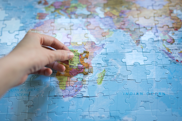 a-hand-with-the-final-piece-of-the-puzzle-putting-it-in-place-on-a-global-map-of-the-planet-with-all t20 1nKKBW