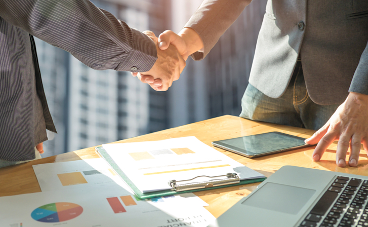 business-concept-two-men-shake-hands-with-document-P2DZLE6