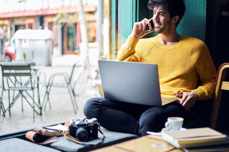 Man werkt remote in café met laptop op schoot