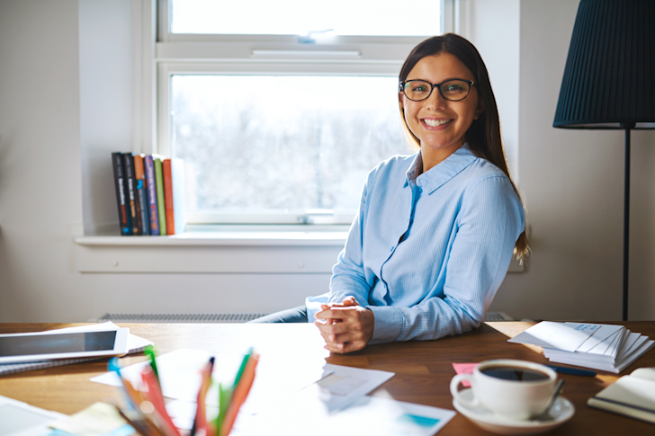 Vrouw lachend achter bureau_wet tegen schijnzelfstandigen in de zorg